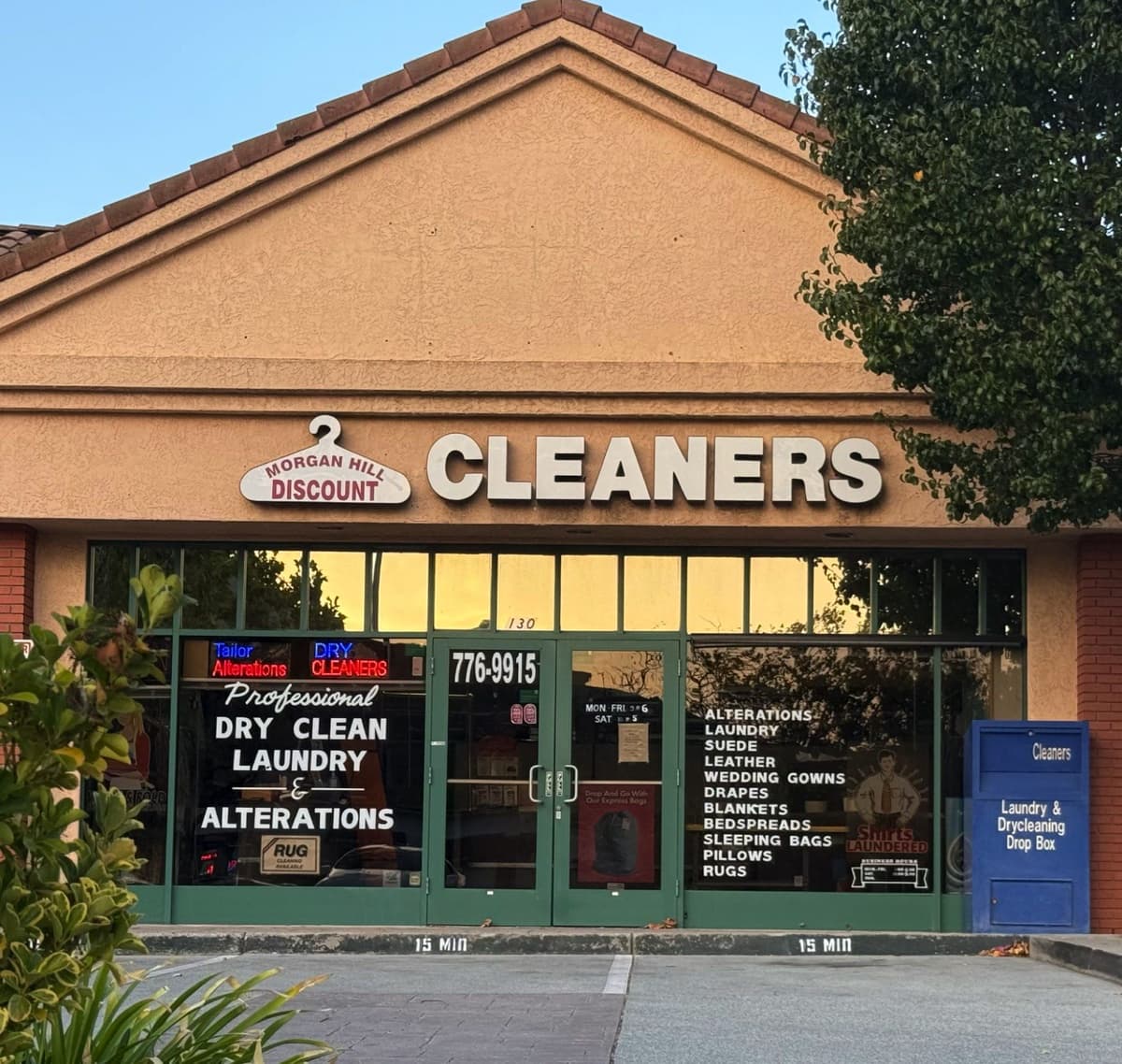 Morgan Hill Discount Cleaners storefront at dusk with the hanger sign lit