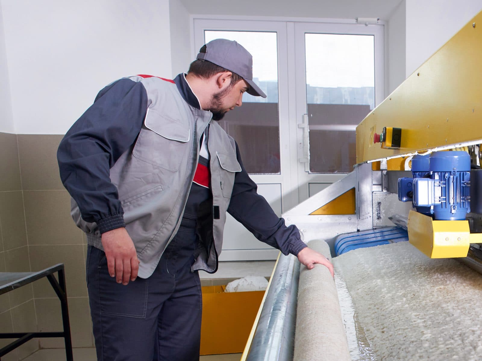 An area rug feeding through an automatic roller washing machine